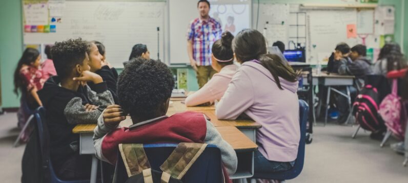 Classroom of students looking at their teaching at the front of the whiteboard.